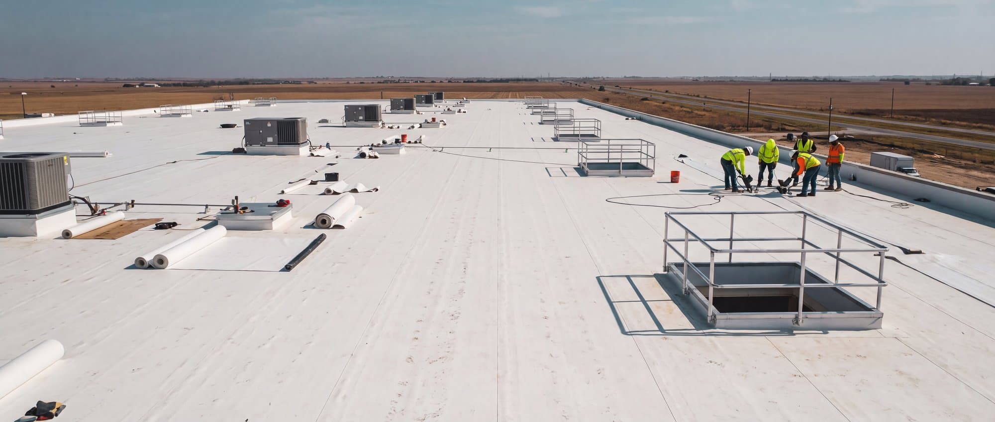 Low drone pass over a warehouse roof during membrane installation